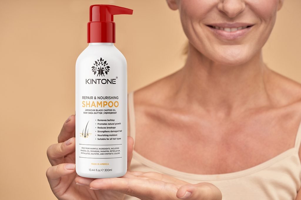 Shop Premium Organic Haircare Products Wholesale: Smiling woman holding Kintone repair and nourishing shampoo.