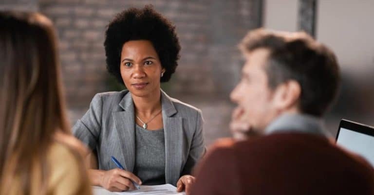 Natural hair discrimination in the workplace: Black female manager having a meeting with two colleagues at work and listening to their concerns.